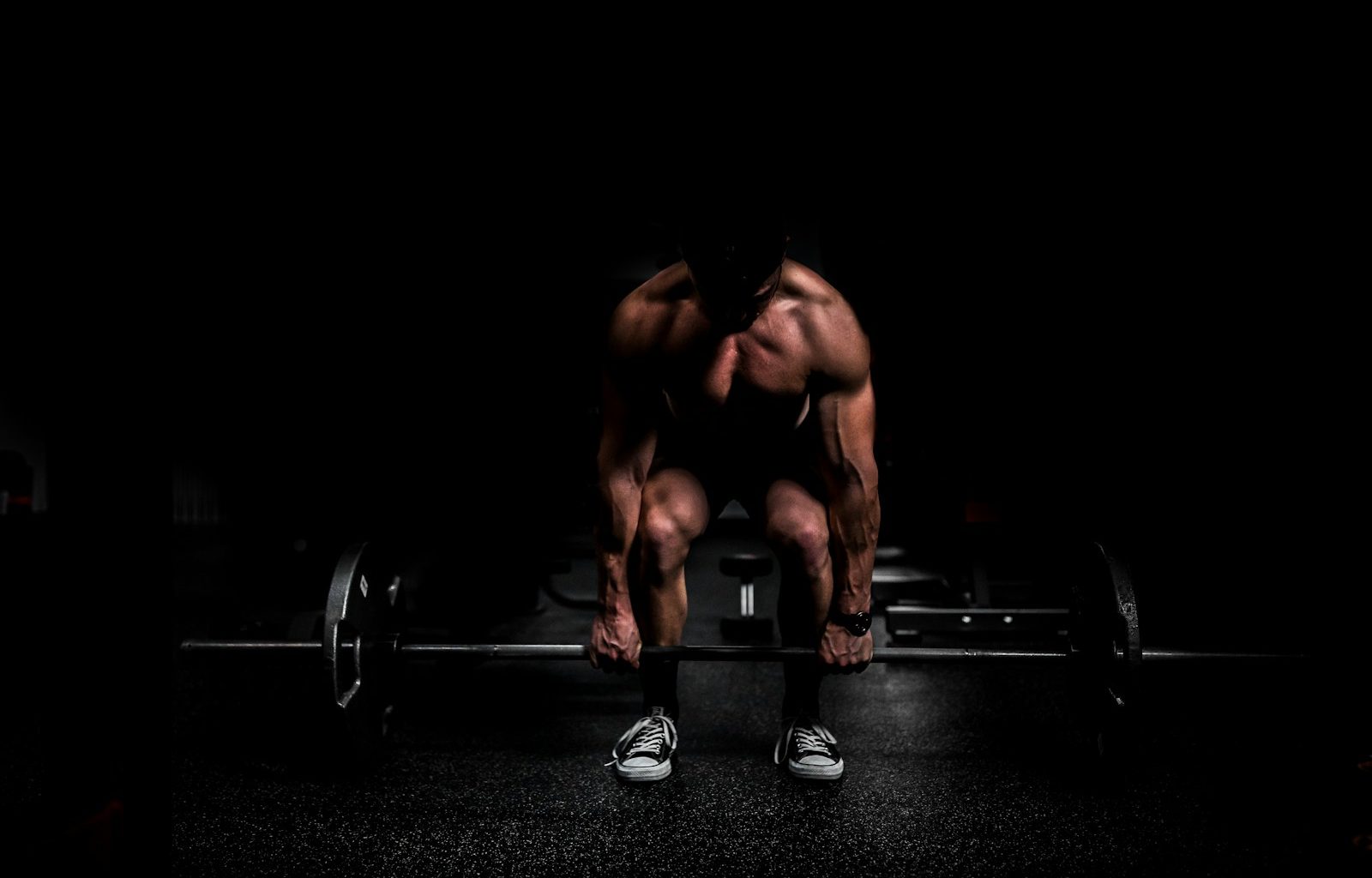 topless man in black shorts sitting on black and silver barbell