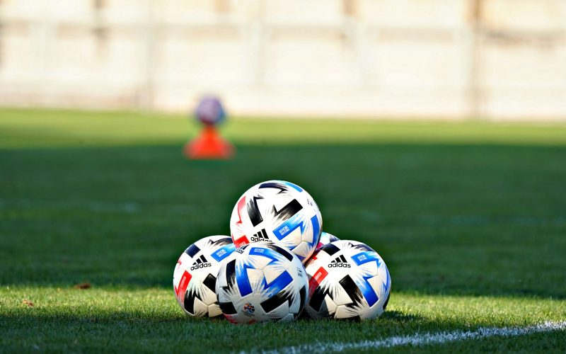 white blue and red soccer ball on green grass field during daytime