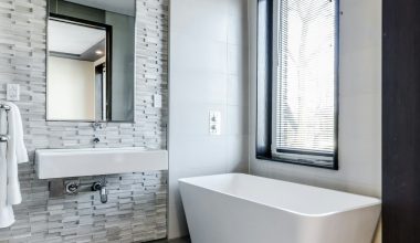 white ceramic bathtub near white framed window