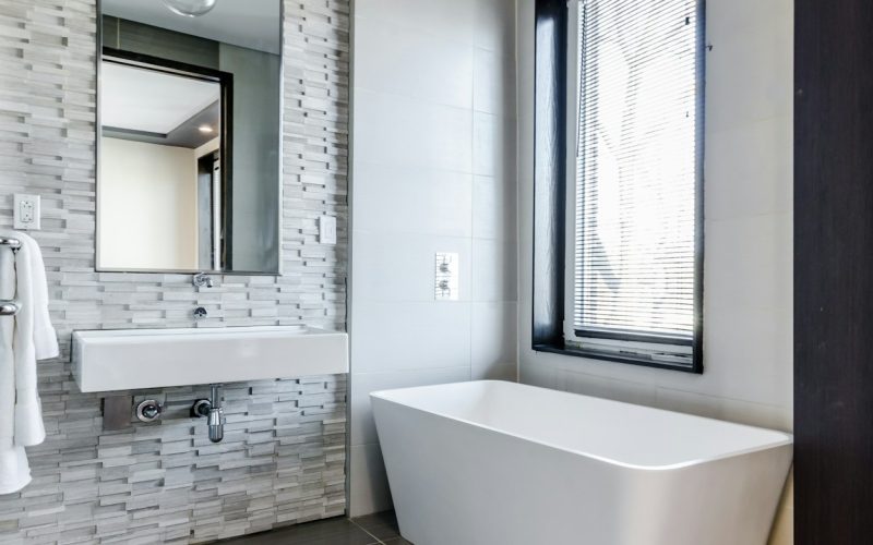 white ceramic bathtub near white framed window