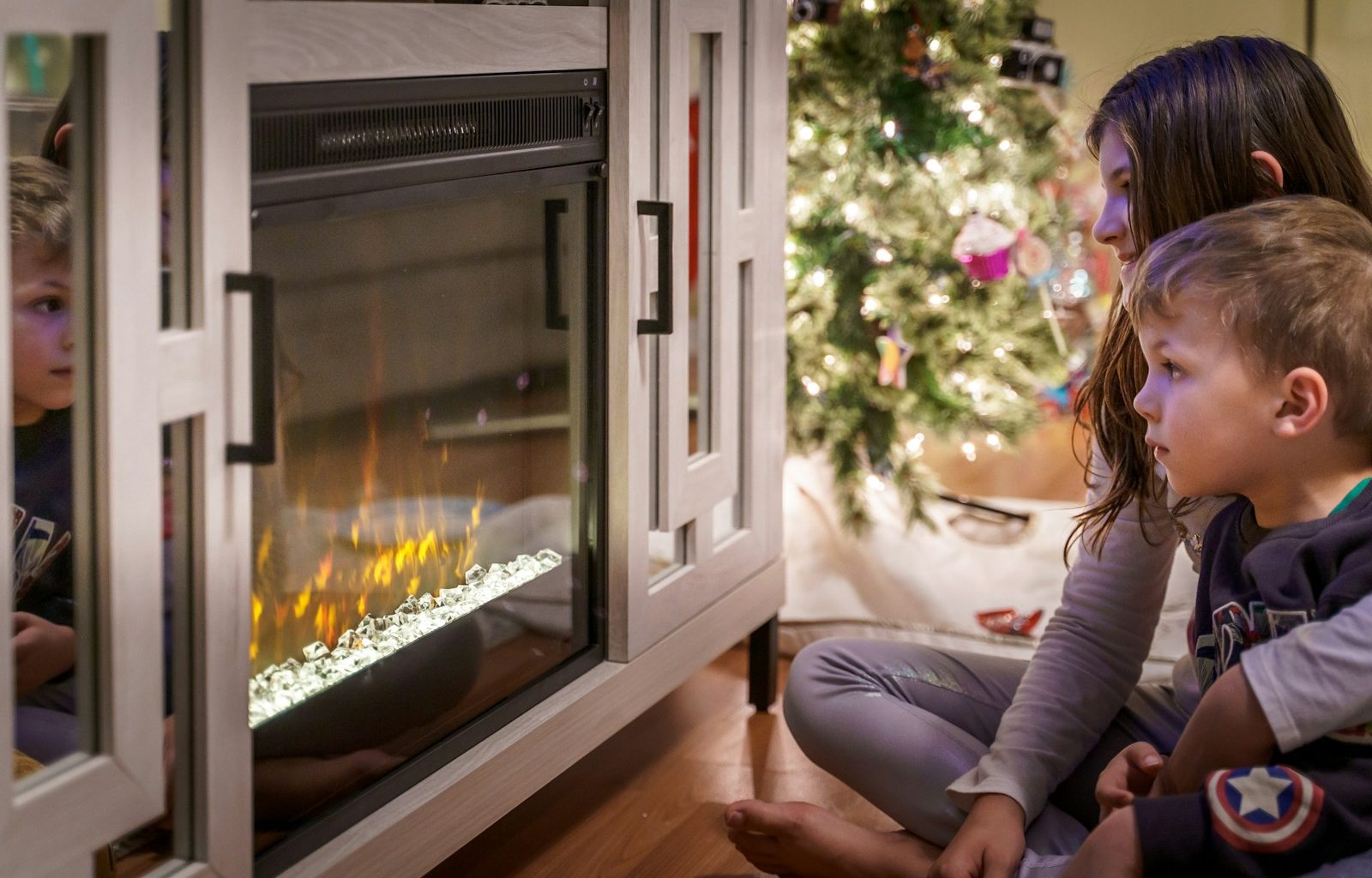 woman in gray long sleeve shirt sitting on floor beside fireplace