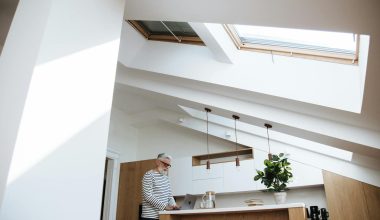 Gray-haired man at home office using laptop in bright kitchen space.
