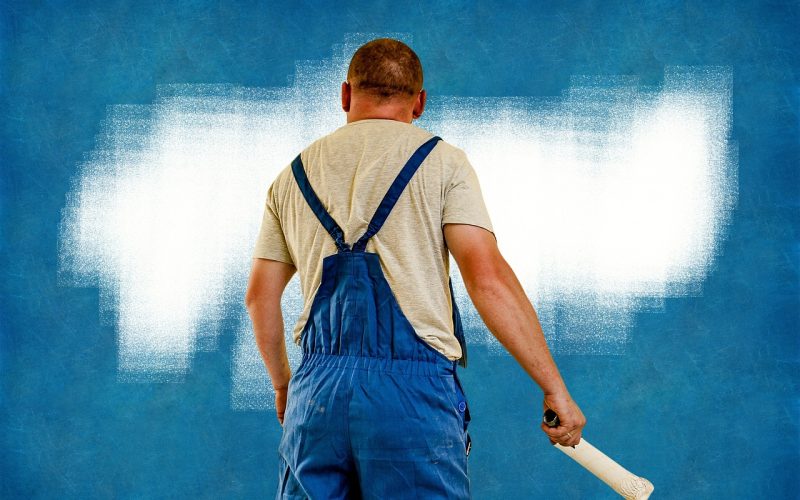 Schilder die een muur wit verft met een roller