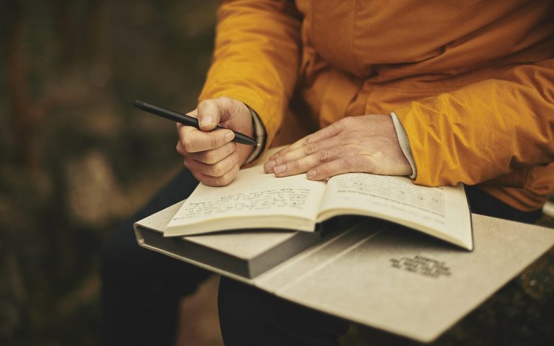 Persoon die notities maakt in een notitieboekje buiten, nadenkend over loopbaanmogelijkheden