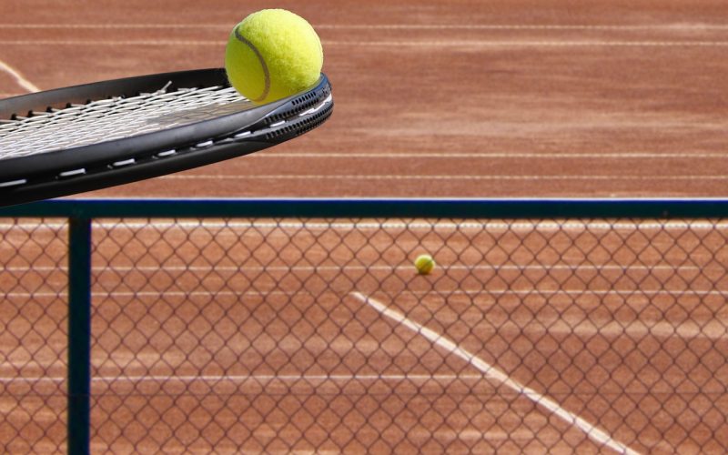Twee spelers op een padelcourt spelen een rally op kunstgras