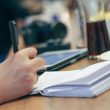 Persoon schrijft een takenlijst aan een bureau om uitstelgedrag aan te pakken