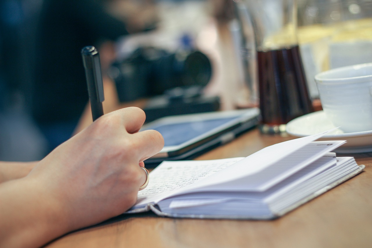 Persoon schrijft een takenlijst aan een bureau om uitstelgedrag aan te pakken