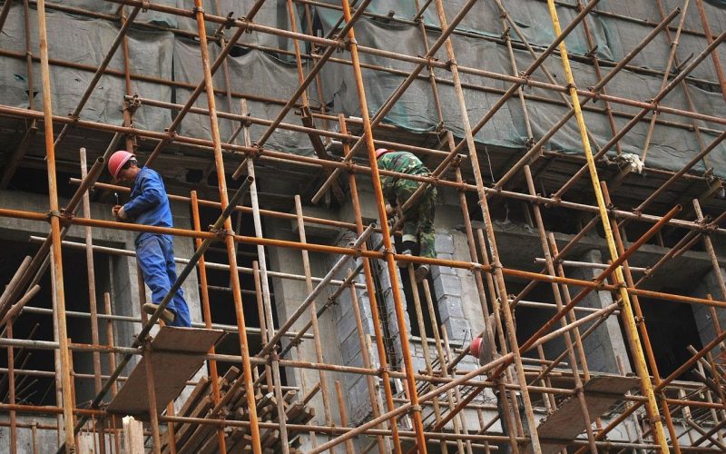 Twee bouwvakkers overleggen op een werkplek, symbolisch voor het inhuren van personeel als zzp'er