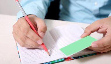 Persoon schrijft aantekeningen in notitieboek aan tafel