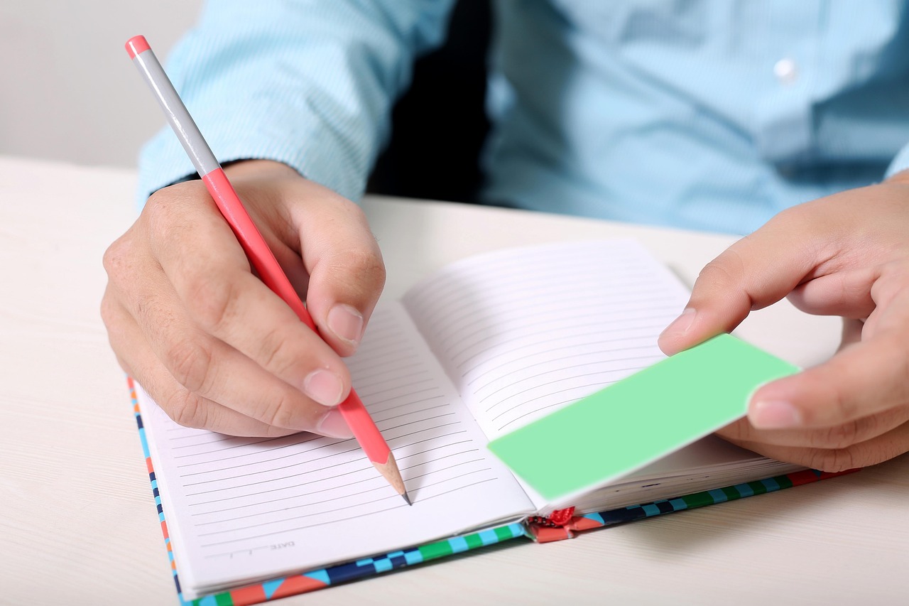 Persoon schrijft aantekeningen in notitieboek aan tafel