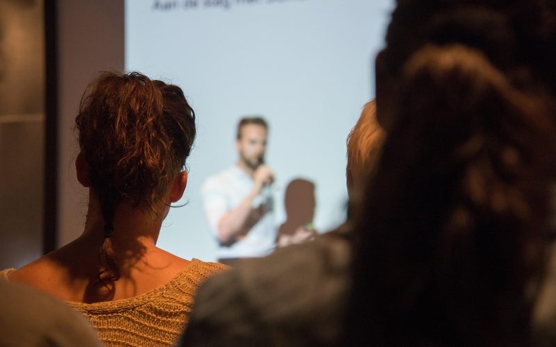 Persoon die zelfverzekerd een presentatie geeft voor een groep collega's in een vergaderzaal